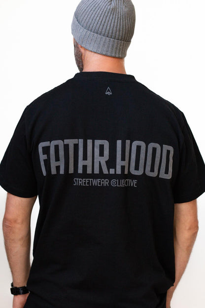 Father wearing a black 'FATHR.HOOD' t-shirt with text on the back.